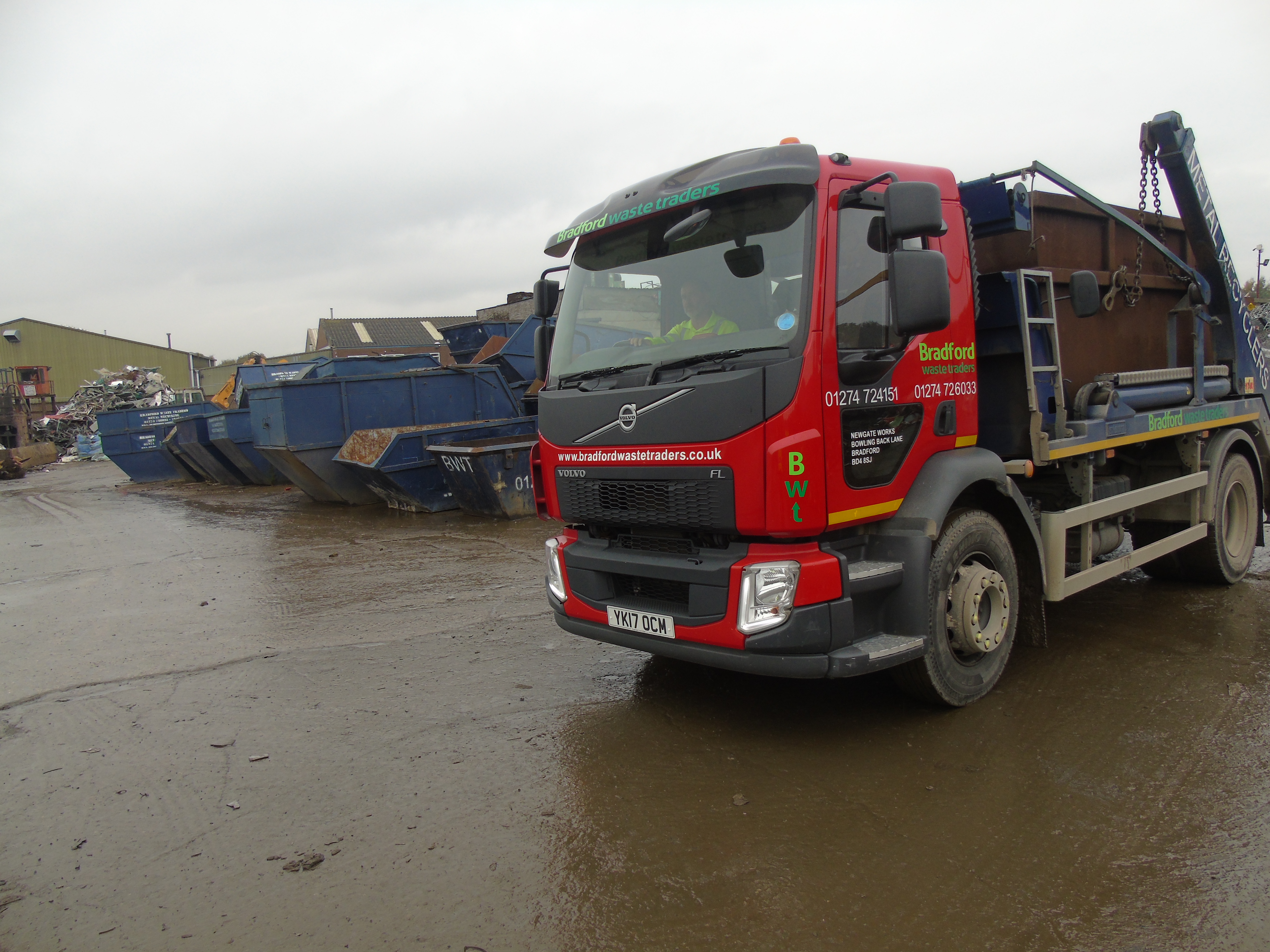 Truck carrying skip, skips in background